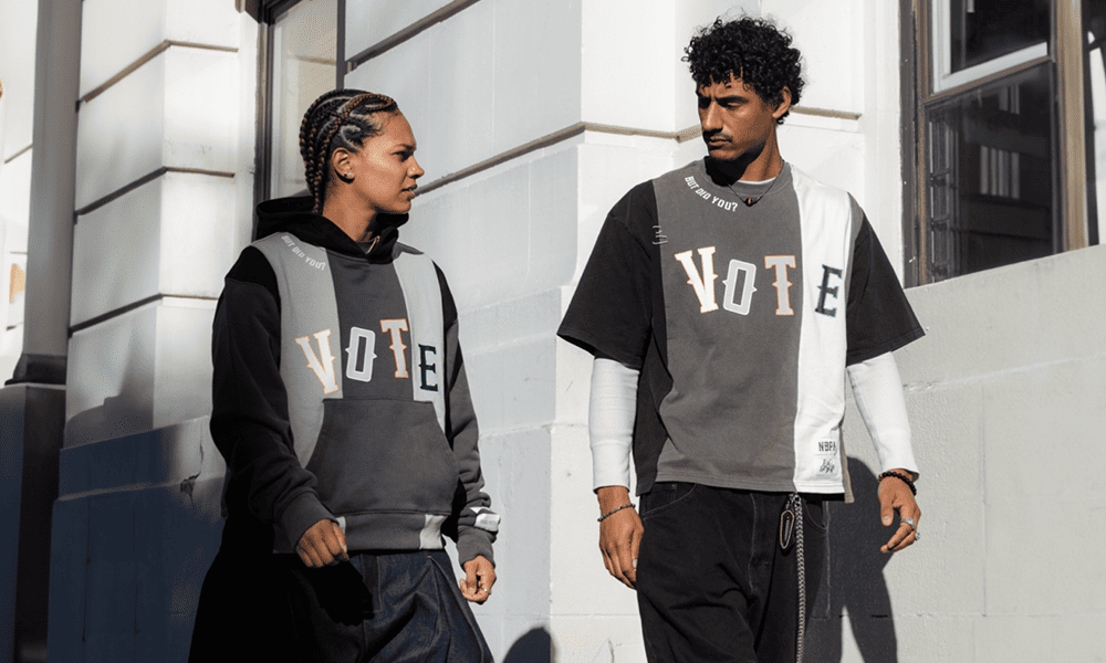 Two people walking down the street wearing top that reads 'Vote'