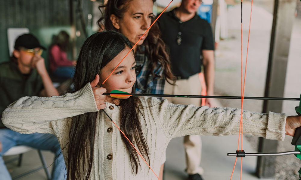 Young girl getting help with archery.